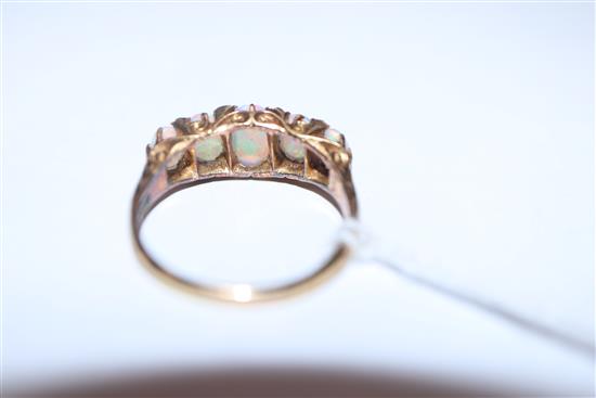 An early 20th century 18ct. gold, graduated five stone white opal and diamond chip half hoop ring, size O.